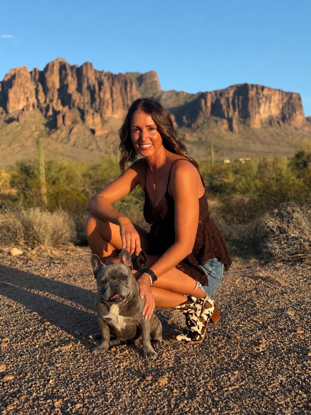 Jen, owner of Desert Paws AZ, holding her French Bulldog Tula in front of the Superstition Mountains near Queen Creek AZ
